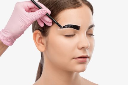 Make up artist makes markings with white pencil for eyebrow and paints eyebrows. Professional makeup and facial care.